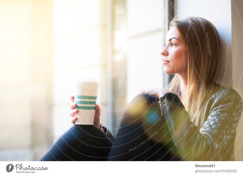 Woman looking through window while holding disposable coffee cup in coffee shop color image colour image indoors indoor shot indoor shots interior interior view
