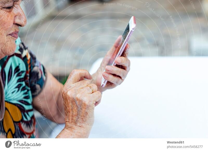 Close-up of senior woman using smart phone at table in yard color image colour image Spain leisure activity leisure activities free time leisure time outdoors