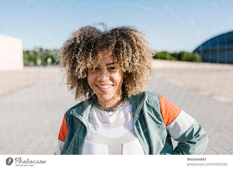 Confident young woman with curly hair during sunny day color image colour image outdoors location shots outdoor shot outdoor shots daylight shot daylight shots