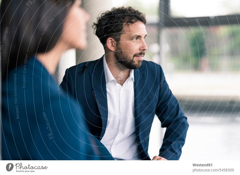 Male entrepreneur looking away by female colleague in lobby color image colour image indoors indoor shot indoor shots interior interior view Interiors day