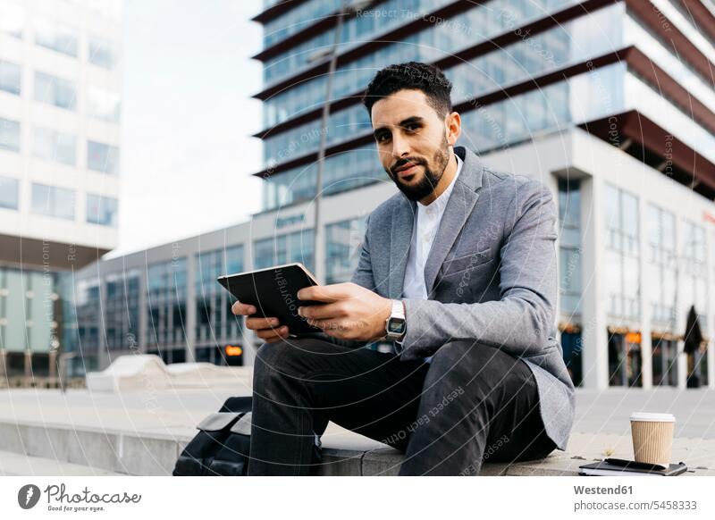 Porrait of a casual young businessman sitting on stairs in the city using tablet Occupation Work job jobs profession professional occupation business life