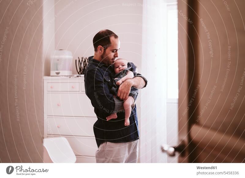 Father carrying cute baby girl in living room at home color image colour image indoors indoor shot indoor shots interior interior view Interiors day