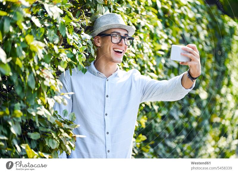 Happy young man taking selfie in a hedge Mixed Race Person mixed-race Person mixed race ethnicity playful wireless Wireless Connection Wireless Technology