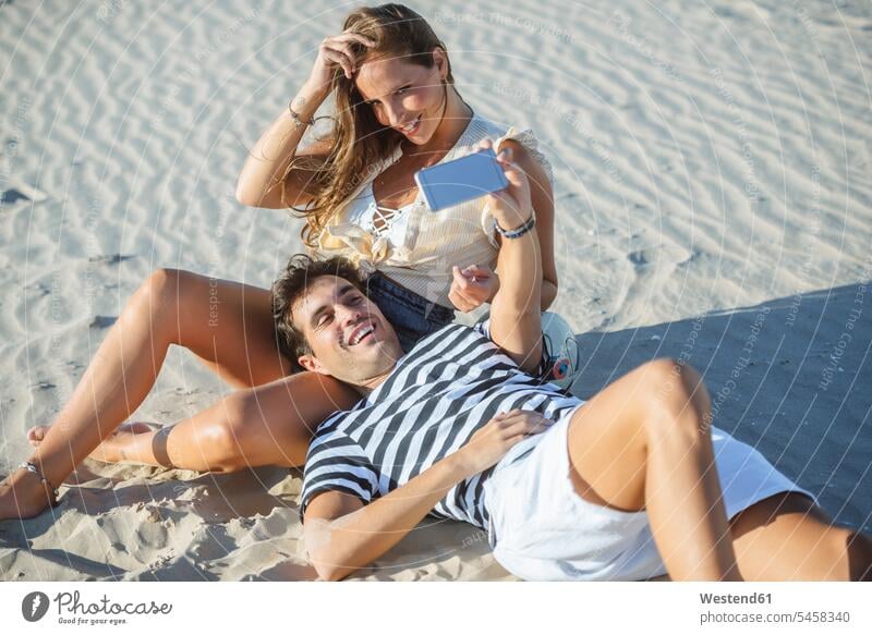 Happy affectionate young couple taking a selfie on the beach Affection Affectionate Selfie Selfies happiness happy smiling smile twosomes partnership couples