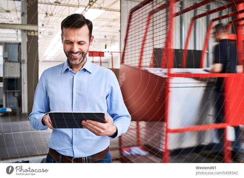 Smiling businessman using tablet in a factory Occupation Work job jobs profession professional occupation business life business world business person