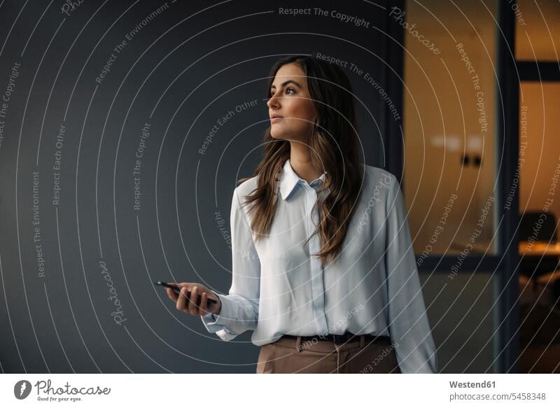 Young businesswoman holding cell phone looking sideways caucasian caucasian ethnicity caucasian appearance european Inspiration Inspiring intuitional Intuition