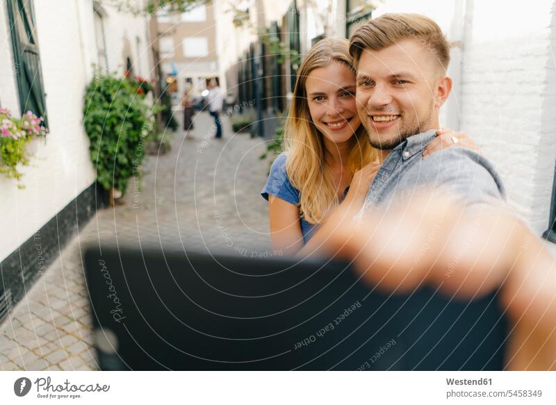Netherlands, Maastricht, happy young couple taking a selfie in the city Selfie Selfies town cities towns happiness twosomes partnership couples outdoors