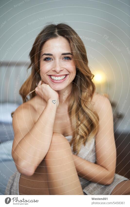 Portrait of happy young woman sitting on bed happiness beds Seated females women portrait portraits Adults grown-ups grownups adult people persons human being