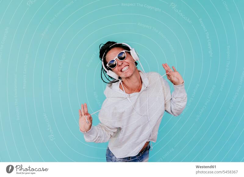 Cheerful woman listening music while pulling strings against turquoise background color image colour image Spain leisure activity leisure activities free time
