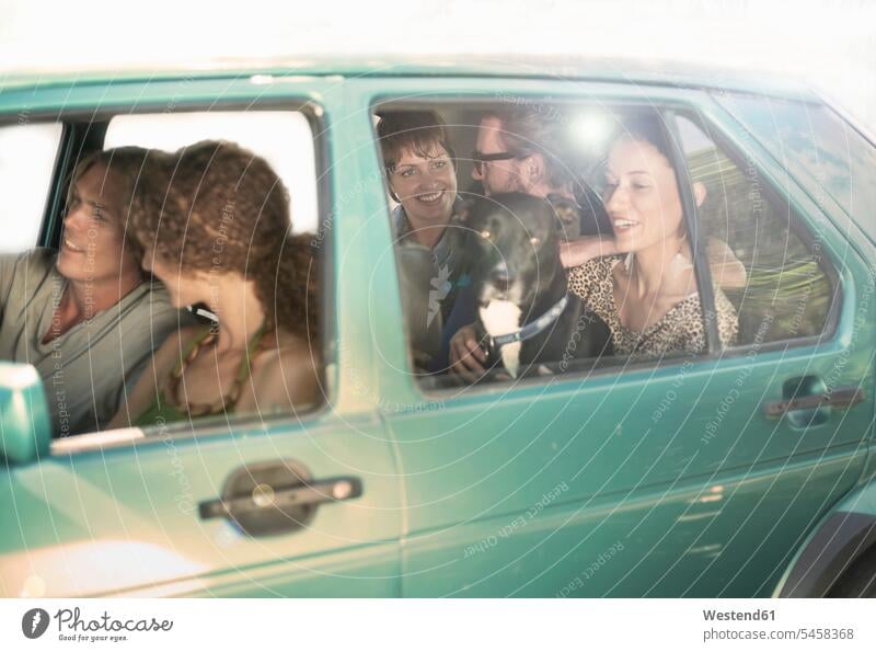 Smiling male and female friends sitting in car during road trip color image colour image outdoors location shots outdoor shot outdoor shots day daylight shot