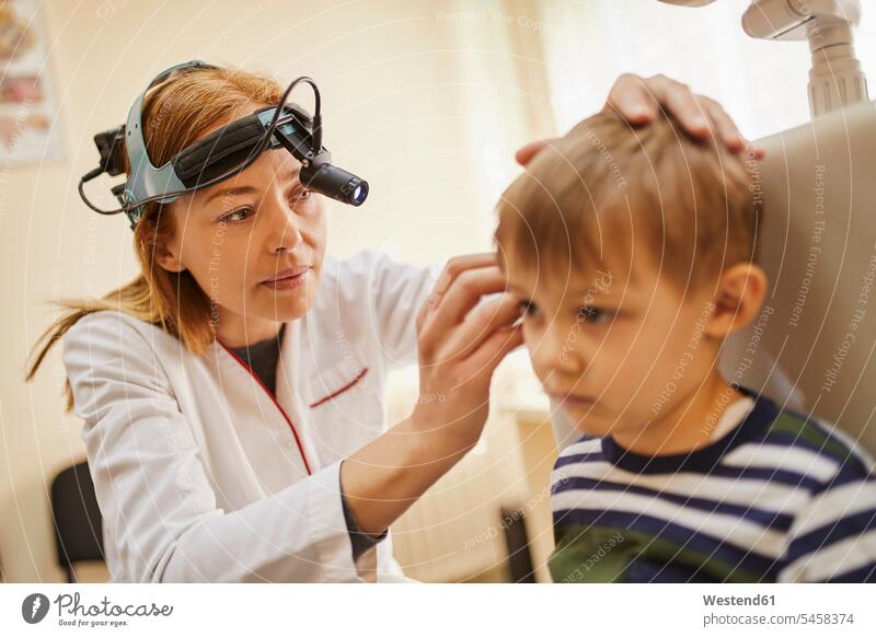 ENT physician examining ear of a boy Female Doctor physicians Female Doctors checking examine ears boys males doctor doctors healthcare and medicine medical