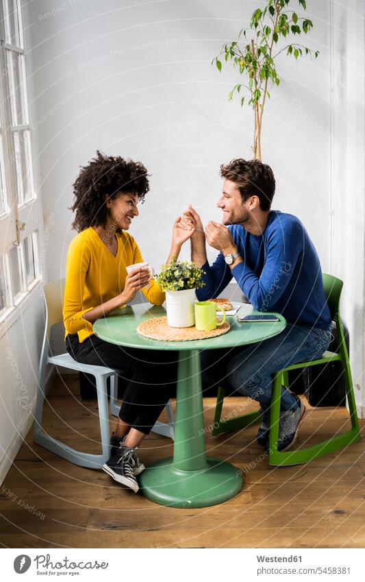 Happy affectionate couple sitting at table at home jumper sweater Sweaters Tables relax relaxing flirt Flirtation smile Seated relaxation delight enjoyment