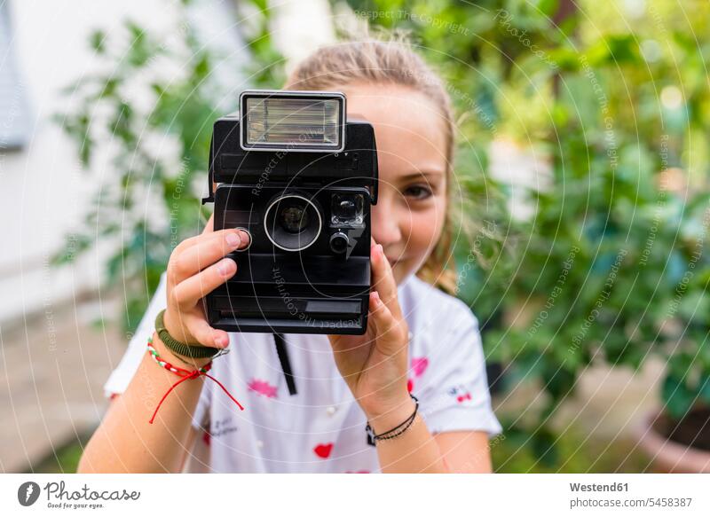 Girl taking a picture with an old-fashioned camera outdoors cameras photograph hold play Retro retro revival Retro Styled Retro-Styled delight enjoyment