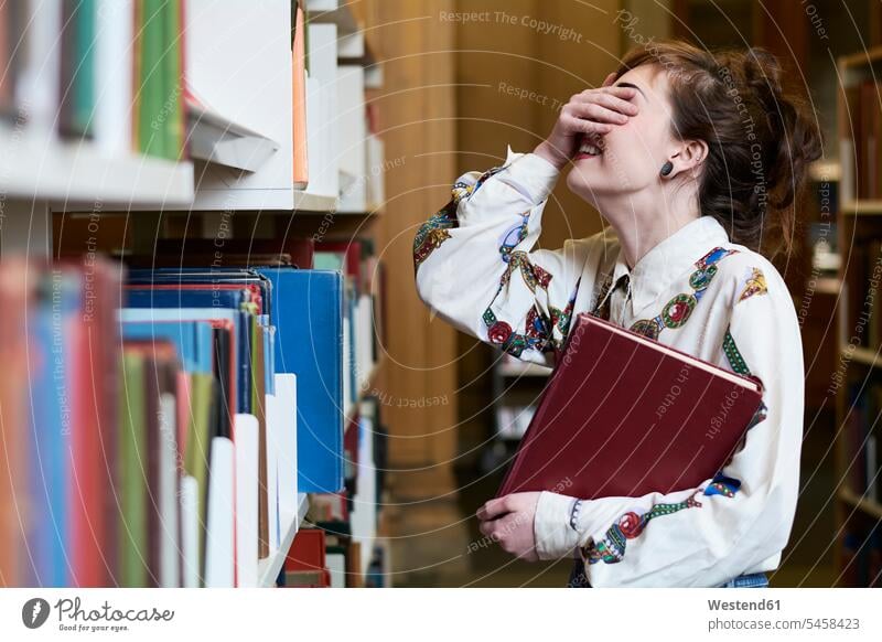 Female student reading book in a public library books woman females women bookworm female students eyes obscured Eyes covered Eye covered Hand Covering Eyes