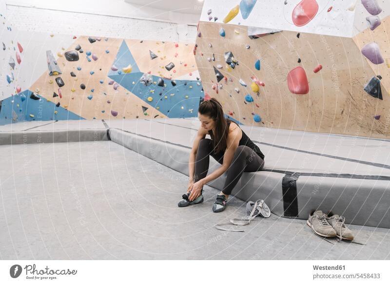 Woman preparing for climbing on the wall putting on shoes (value=0) exercise practising train training Seated sit free time leisure time Recreational Activities
