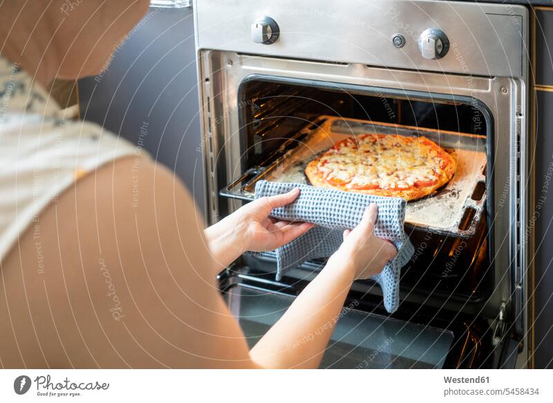 Crop view of woman taking tray with baked pizza out of oven pull at home heat Hot Temperature free time leisure time Lifestyle Alimentation food Food and Drinks