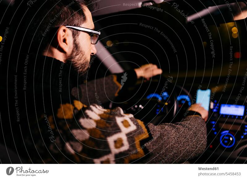Man using cell phone with road maps in the car at night by night nite night photography man men males mobile phone mobiles mobile phones Cellphone cell phones