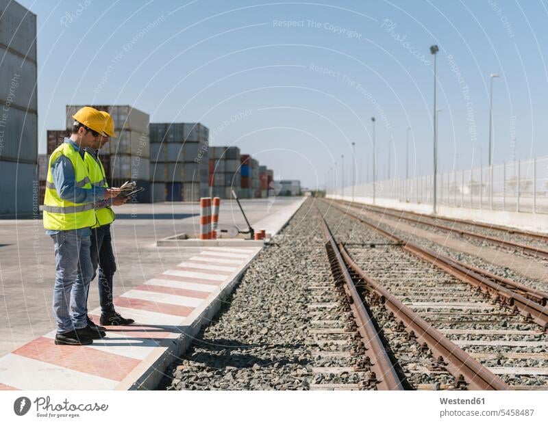 Workers in front of cargo containers near railway tracks on industrial site Spain safety at work occupational health and safety occupational safety and health