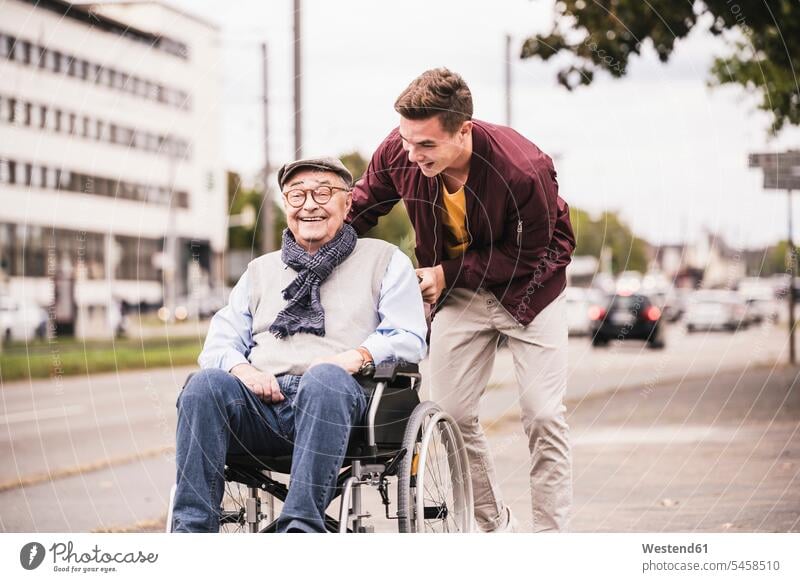 Young man pushing happy senior man in wheelchair human human being human beings humans person persons caucasian appearance caucasian ethnicity european 2