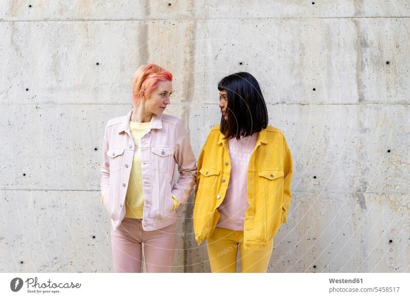 Two alternative friends having fun, wearing yellow and pink jeans clothes, face to face female friends Alternative homosexual woman lesbians gay women gay woman