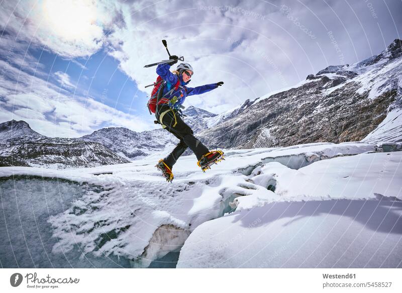 Female mountaineer jumping over crevasse, Glacier Grossvendediger, Tyrol, Austria human human being human beings humans person persons caucasian appearance