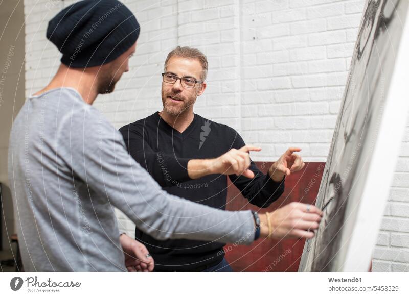 Artist discussing drawing with man in studio studios discussion drawings artist artists men males image images picture pictures Adults grown-ups grownups adult