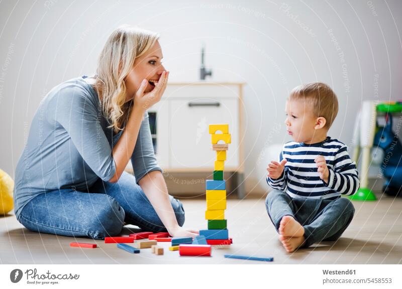 Happy mother and toddler son playing with building blocks at home happiness happy sons manchild manchildren mommy mothers mummy mama family families people