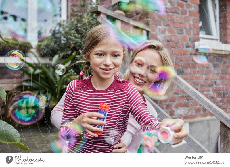 Happy mother and daughter making soap bubbles sitting Seated happiness happy house houses home at home mommy mothers mummy mama daughters stairs stairway