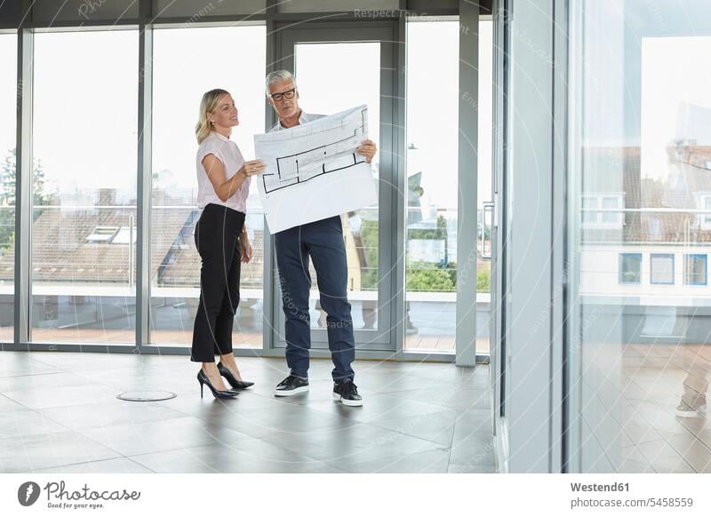 Businessman and woman standing in office, discussing blueprint discussion Meeting Meetings Business Meeting businesswoman businesswomen business woman