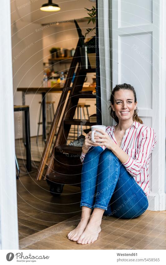 Portrait of smiling woman sitting on the floor at home with cup of coffee Coffee Cup Coffee Cups portrait portraits females women floors smile Seated Adults