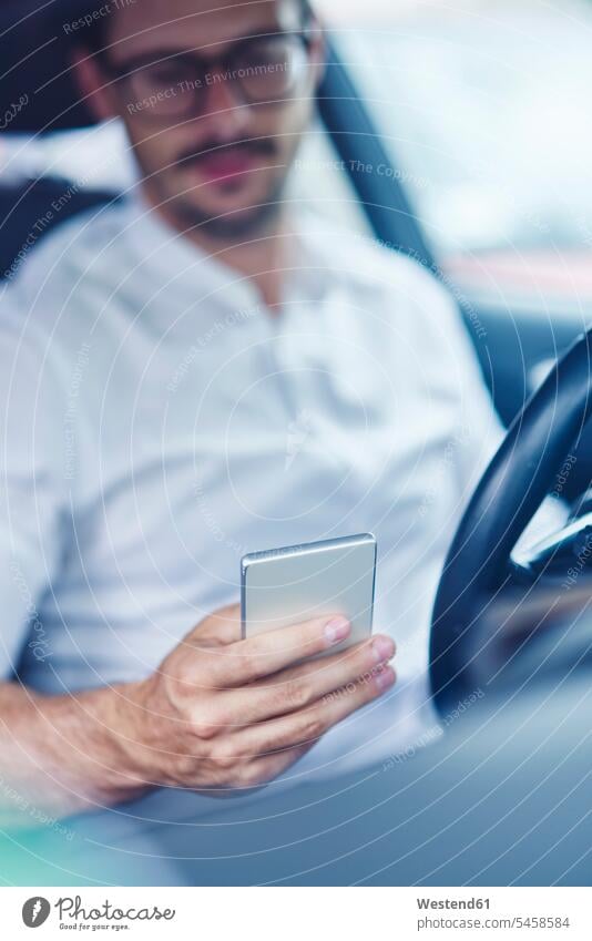 Hand of businessman sitting in car holding cell phone hand human hand hands human hands Seated Smartphone iPhone Smartphones Businessman Business man