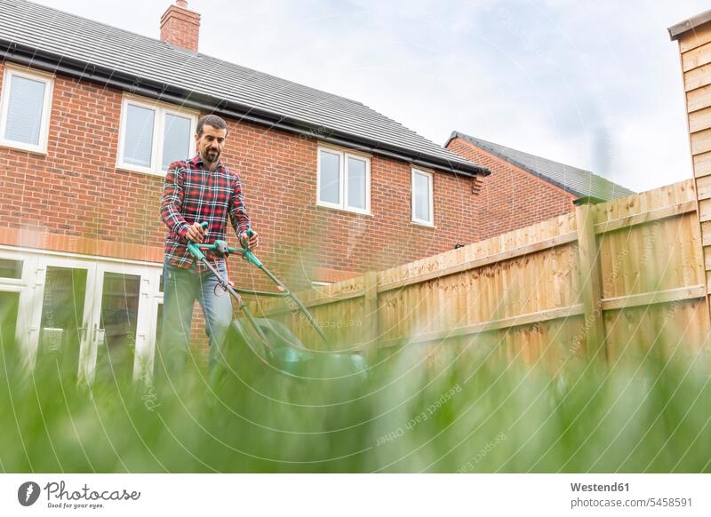 Man mowing lawn with lawn mower at backyard color image colour image outdoors location shots outdoor shot outdoor shots day daylight shot daylight shots