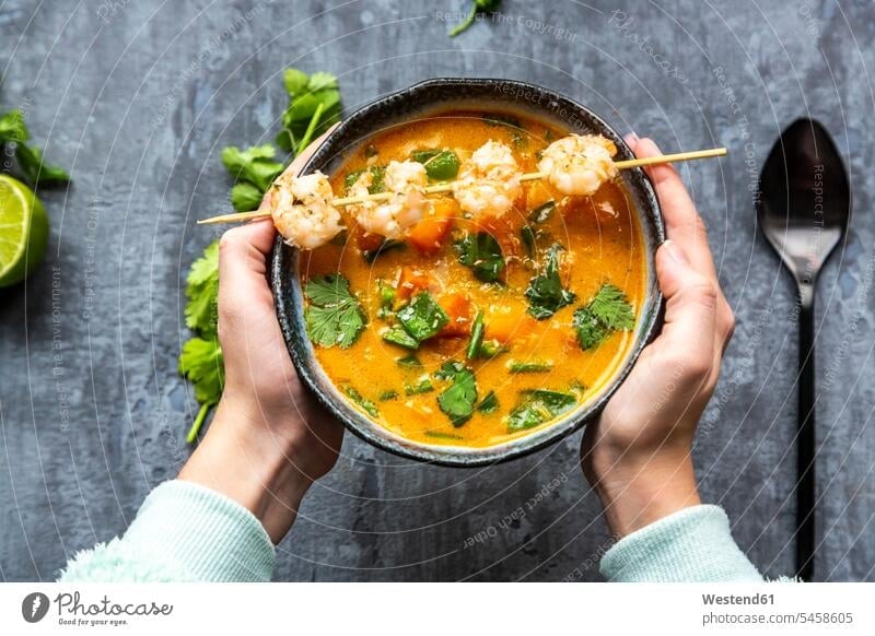 Girl's hands holding bowl of sweet potato soup with shrimps, coconut flakes and fresh coriander Bowl Bowls human hand human hands Dishes Crockery Tableware