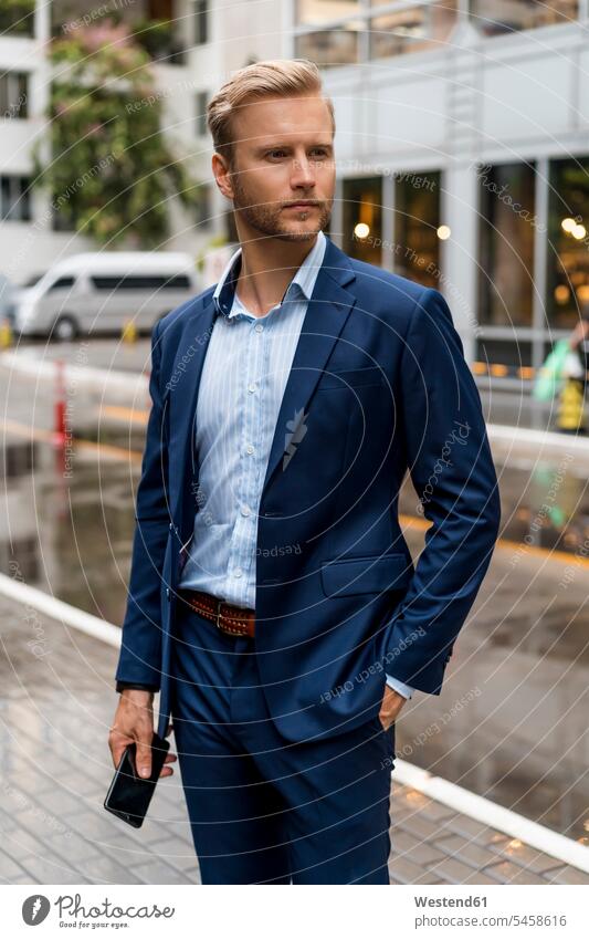 Young businessman with smartphone during a rainy day in Bangkok human human being human beings humans person persons caucasian appearance caucasian ethnicity