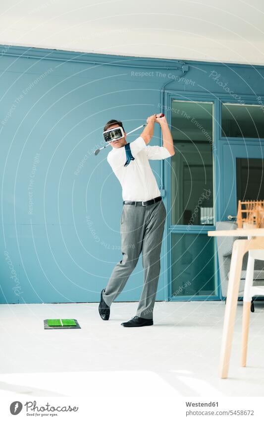 Businessman wearing VR glasses playing golf in office Virtual Reality Business man Businessmen Business men specs Eye Glasses spectacles Eyeglasses golfing
