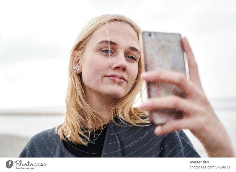 Portrait of blond young woman taking selfie with smartphone on the beach portrait portraits Selfie Selfies blond hair blonde hair females women Smartphone