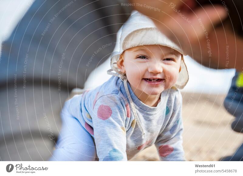 Spain, Lanzarote, portrait of laughing baby girl playing with father on the beach infants nurselings babies beaches daughter daughters Laughter portraits