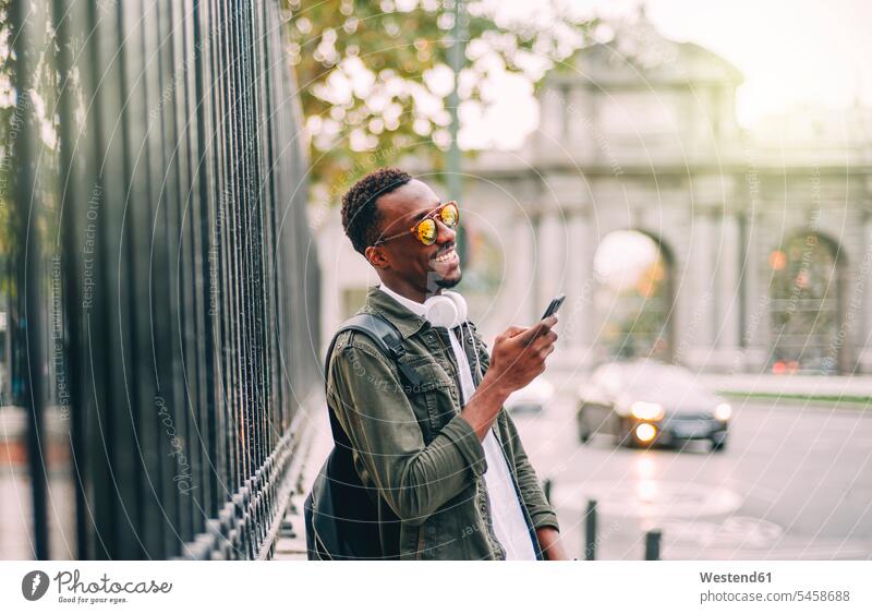Smiling man wearing sunglasses using smart phone while standing in city color image colour image Spain leisure activity leisure activities free time