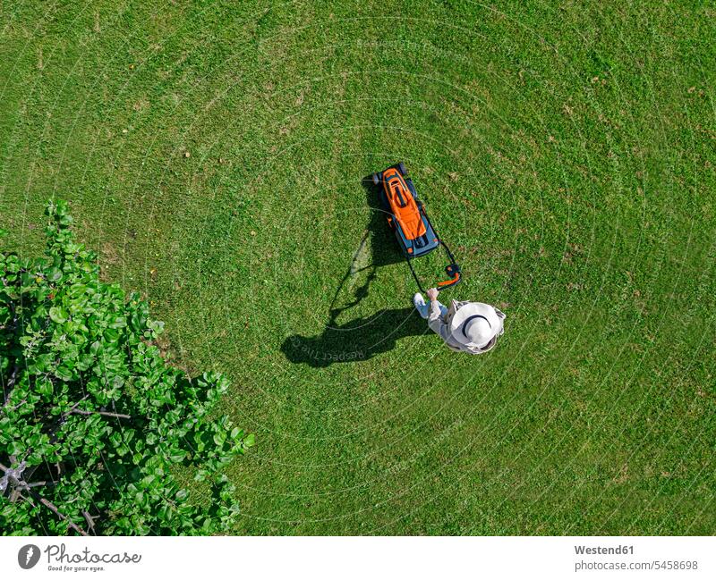 Woman with lawn mower standing in back yard color image colour image outdoors location shots outdoor shot outdoor shots day daylight shot daylight shots