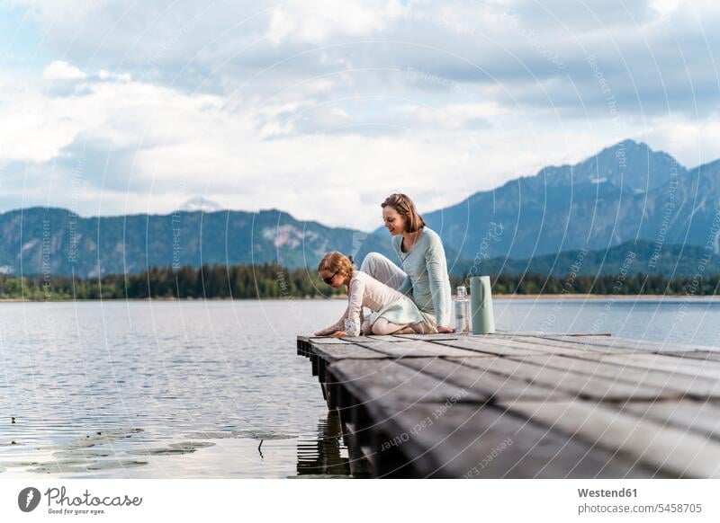 Mother with daughter sitting on jetty over lake against sky color image colour image Germany leisure activity leisure activities free time leisure time