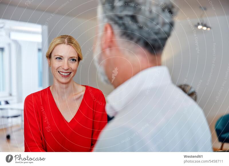 Smiling young woman looking at mature colleague in office colleagues Female Colleague offices office room office rooms eyeing smiling smile workplace work place