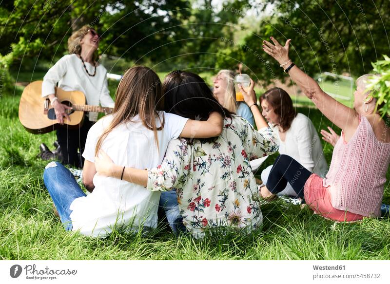 Group of women with guitar having fun at a picnic in park Fun funny woman females Picnic picnicking parks female friends happiness happy guitars Adults
