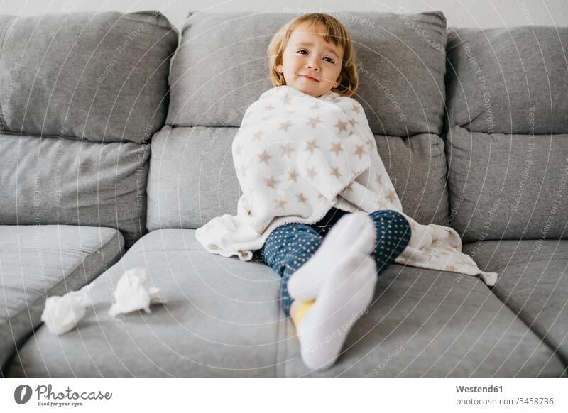 Portrait of sick little girl sitting on the couch at home wrapped in blanket Blankets stockings sock couches settee settees sofa sofas handkerchiefs Seated