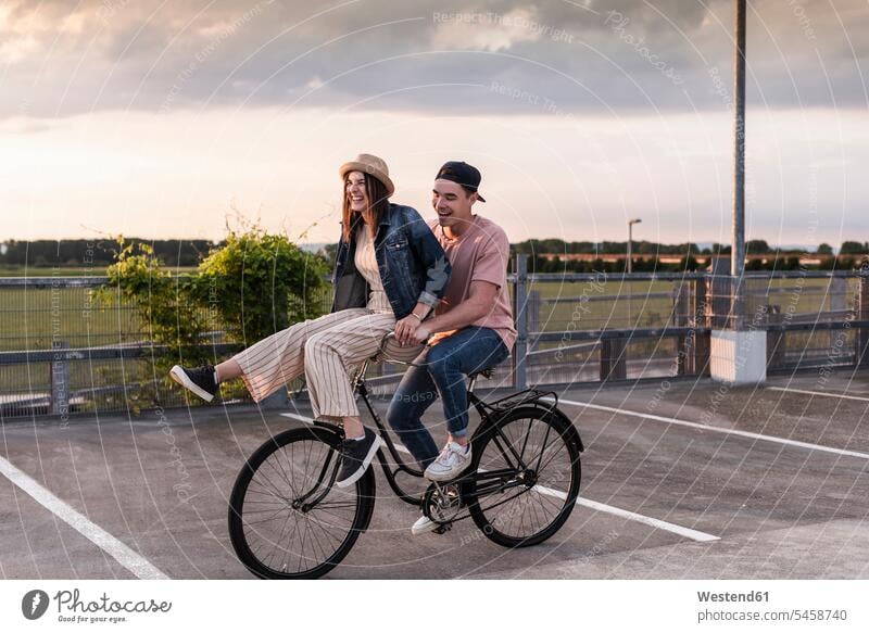 Happy young couple together on a bicycle on parking deck human human being human beings humans person persons caucasian appearance caucasian ethnicity european