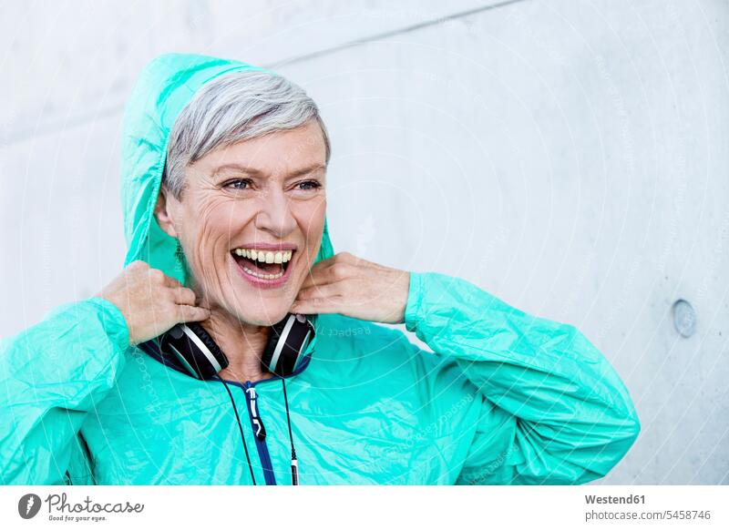 Portrait of laughing sporty mature woman with headphones portrait portraits sportive sporting athletic Laughter headset females women sports positive Emotion