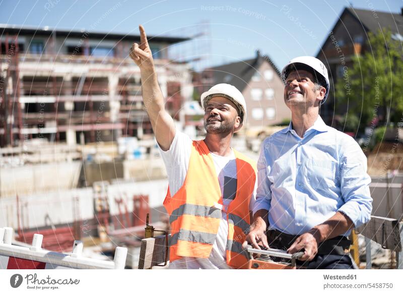 Smiling construction worker talking to man on construction site smiling smile men males Building Site sites Building Sites construction sites builders speaking