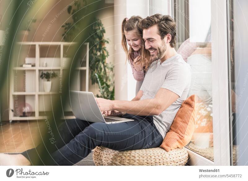 Young man and little girl surfing the net together Germany Selective focus Differential Focus sitting on ground Sitting On The Floor Sitting On Floor