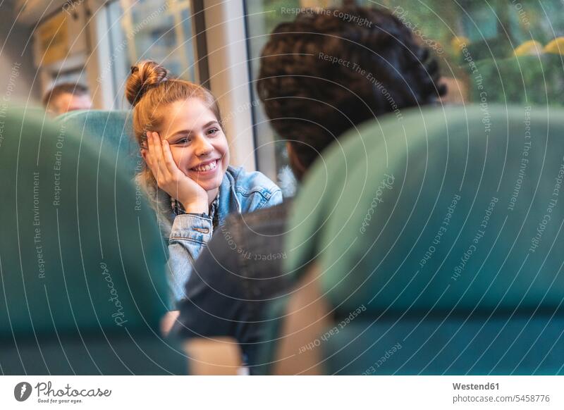 Portrait of happy young woman travelling by train with her boyfriend, London, UK flirt Flirtation smile Seated sit free time leisure time Lifestyle mobile