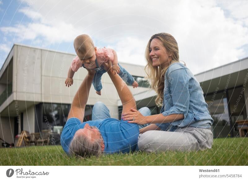 Happy father with mother lifting up baby girl in garden human human being human beings humans person persons caucasian appearance caucasian ethnicity european