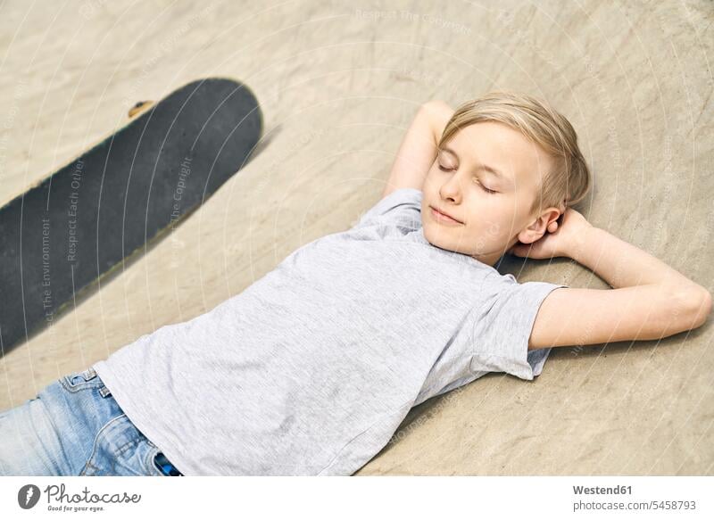Boy relaxing in skatepark skateboard Skate Board skateboards boy boys males relaxation relaxed lying laying down lie lying down leisure free time leisure time